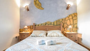 Una cama con una colcha estampada, dos lámparas de noche y una pared con diseño de luna creciente.