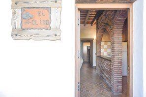Un couloir avec une enseigne en bois portant l’inscription « EL OLIVO », des colonnes en briques et un sol carrelé.