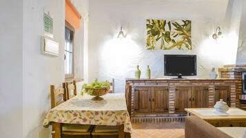A dining area with a table set for two, a television, and a brick fireplace.