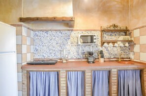 Une cuisine équipée d’un four à micro-ondes, d’une machine à café et d’étagères où sont rangés la vaisselle.