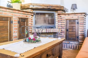 A cozy room with a brick fireplace, wooden cabinets, and a television. - Apartment 'El Nogal' with Shared Pool, Wi-Fi and Air Conditioning (Barbate)