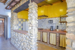 A kitchen with stone walls, yellow walls, a tiled backsplash, and a wooden ceiling. - Apartment 'El Nogal' with Shared Pool, Wi-Fi and Air Conditioning (Barbate)
