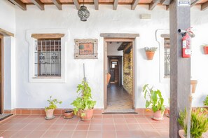 A building entrance with a sign reading 'EL NOGAL,' potted plants, a fire extinguisher, and a tiled floor.