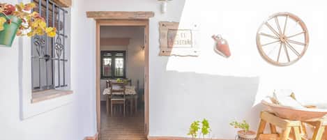 Un patio con una mesa, sillas, una maceta colgante, un letrero que dice 'EL CASTAÑO' y una rueda de madera.