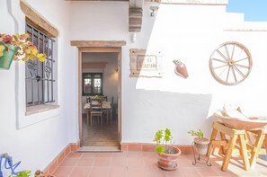 A patio with a table, chairs, a hanging flower pot, a sign reading 'EL CASTAÑO,' and a wooden wheel. - Apartment 'Castaño' with Shared Pool, Wi-Fi and Air Conditioning (Barbate)