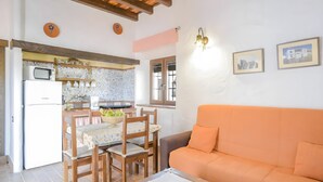 A living room with a sofa and a dining area with chairs and a table. - Apartment 'Castaño' with Shared Pool, Wi-Fi and Air Conditioning (Barbate)