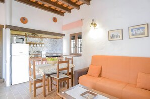 A living room with a sofa and a dining area with chairs and a table. - Apartment 'Castaño' with Shared Pool, Wi-Fi and Air Conditioning (Barbate)