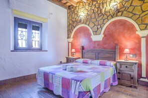 A bedroom with a bed, two nightstands, a stone wall, and a window with a curtain. - Apartment 'Castaño' with Shared Pool, Wi-Fi and Air Conditioning (Barbate)