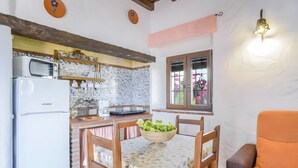 A kitchen with a microwave, refrigerator, and a dining table with a bowl of salad. - Apartment 'Castaño' with Shared Pool, Wi-Fi and Air Conditioning (Barbate)