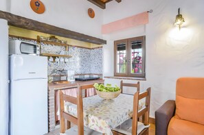 A kitchen with a microwave, refrigerator, and a dining table with a bowl of salad. - Apartment 'Castaño' with Shared Pool, Wi-Fi and Air Conditioning (Barbate)