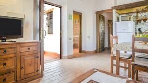 A kitchen with a microwave, refrigerator, and wooden chairs. - Apartment 'Castaño' with Shared Pool, Wi-Fi and Air Conditioning (Barbate)
