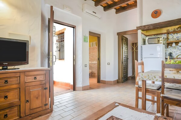 A kitchen with a microwave, refrigerator, and wooden chairs. - Apartment 'Castaño' with Shared Pool, Wi-Fi and Air Conditioning (Barbate)