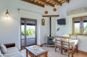 Una habitación acogedora con sofá, mesa de madera, sillas, chimenea y televisión.