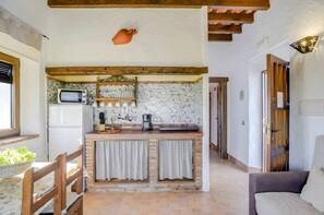 A kitchen with a microwave, coffee maker, and a small island with curtains.