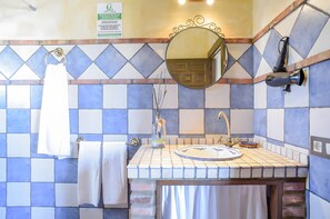 A bathroom with a tiled wall, a sink with a mirror, a towel rack, and a hairdryer. - Apartment 'El Manzano' with Shared Pool, Wi-Fi and Air Conditioning (Barbate)