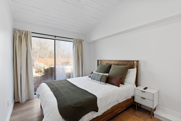 A bedroom with a large bed, wooden headboard, and a nightstand with a phone.