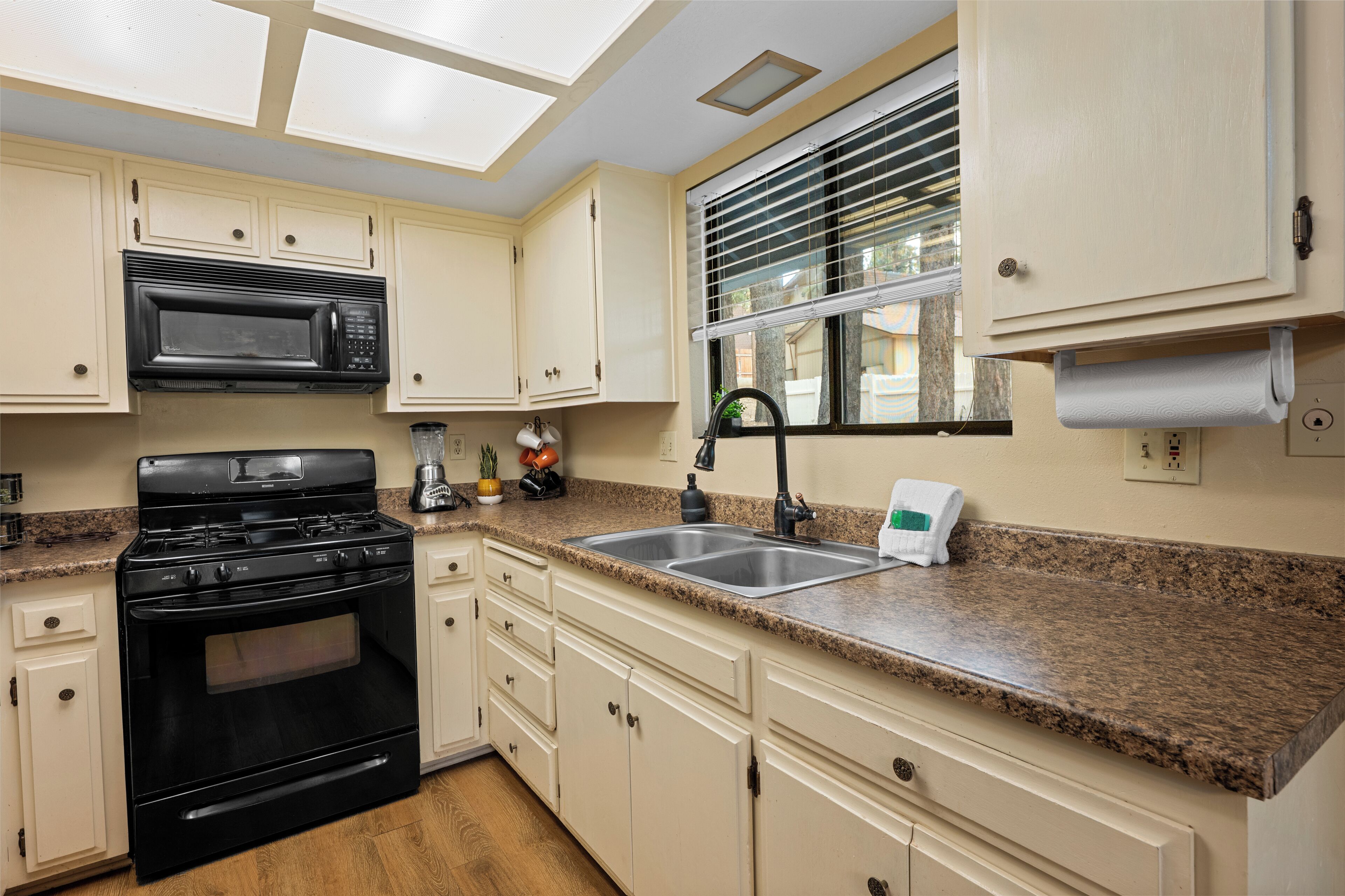 A kitchen with white cabinets, a black stove, a microwave, and a granite countertop.