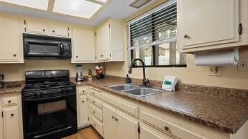 A kitchen with white cabinets, a black stove, a microwave, and a granite countertop.
