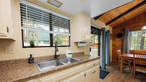 Una cocina con encimera de granito, un lavamanos doble y una zona de comedor con mesa y sillas de madera.