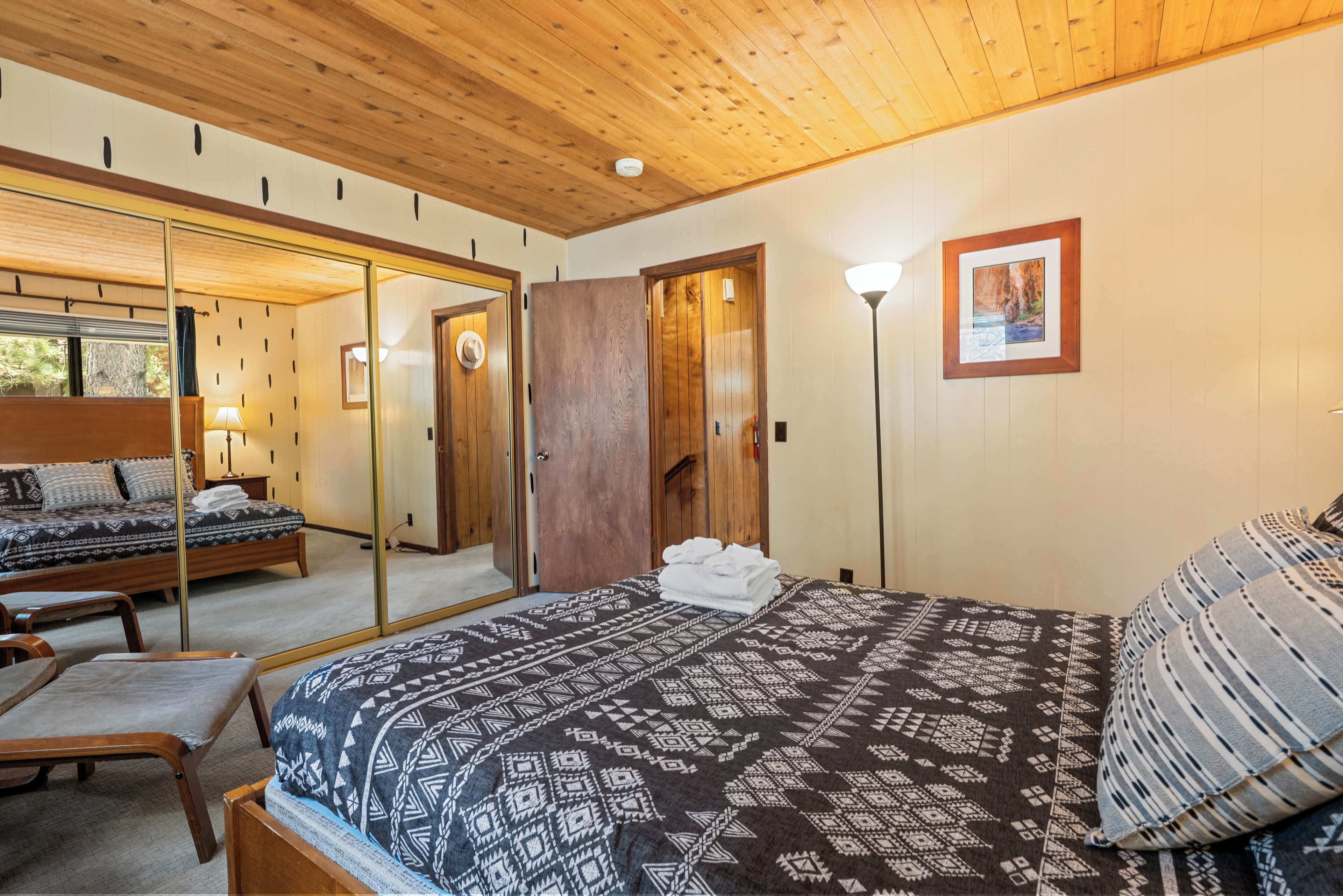 Une chambre avec un grand lit, un plafond en bois et un miroir.
