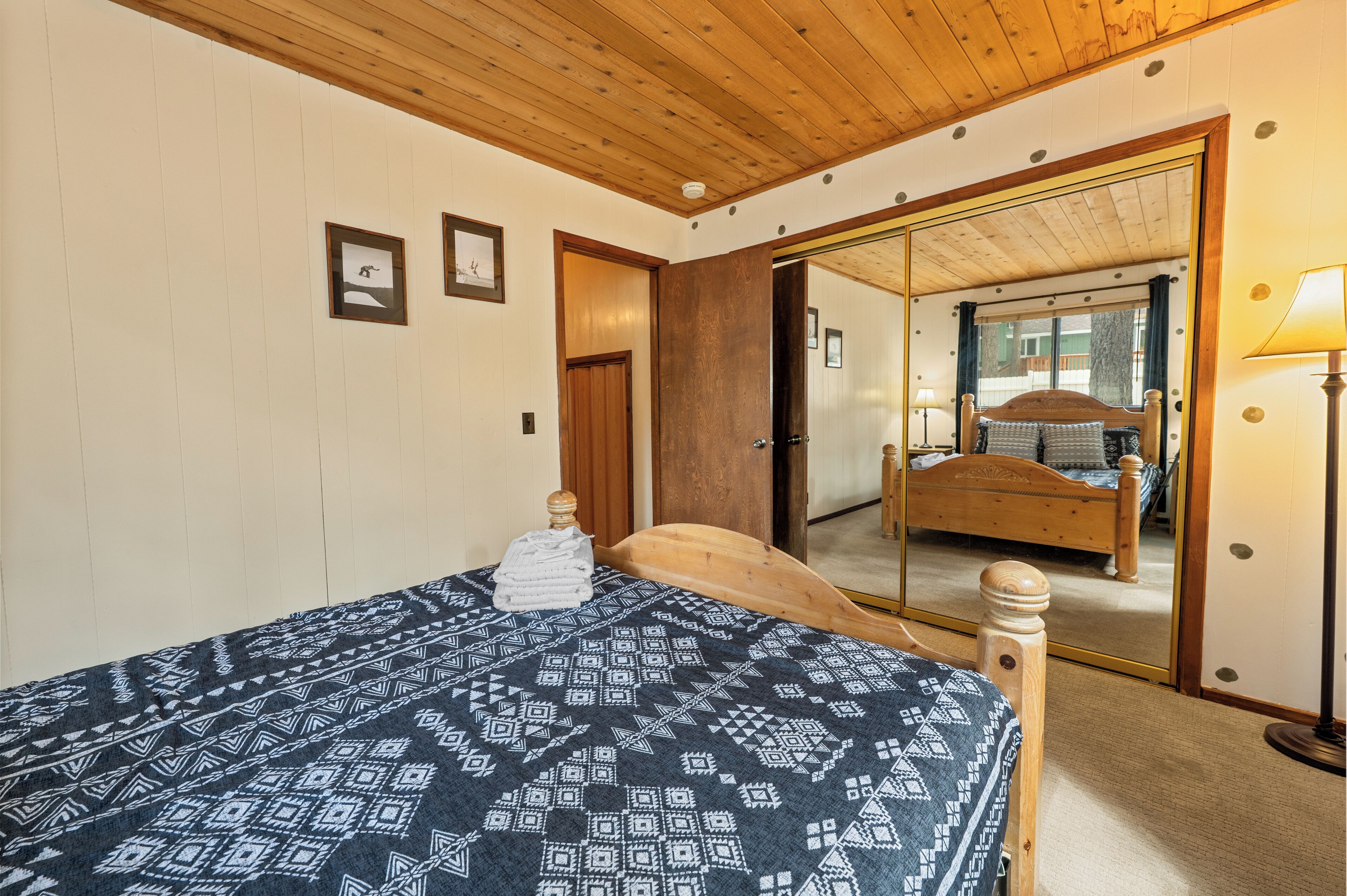 Ein Schlafzimmer mit einem Bett, einem Holzkopfteil, einem Spiegel und einer Lampe.