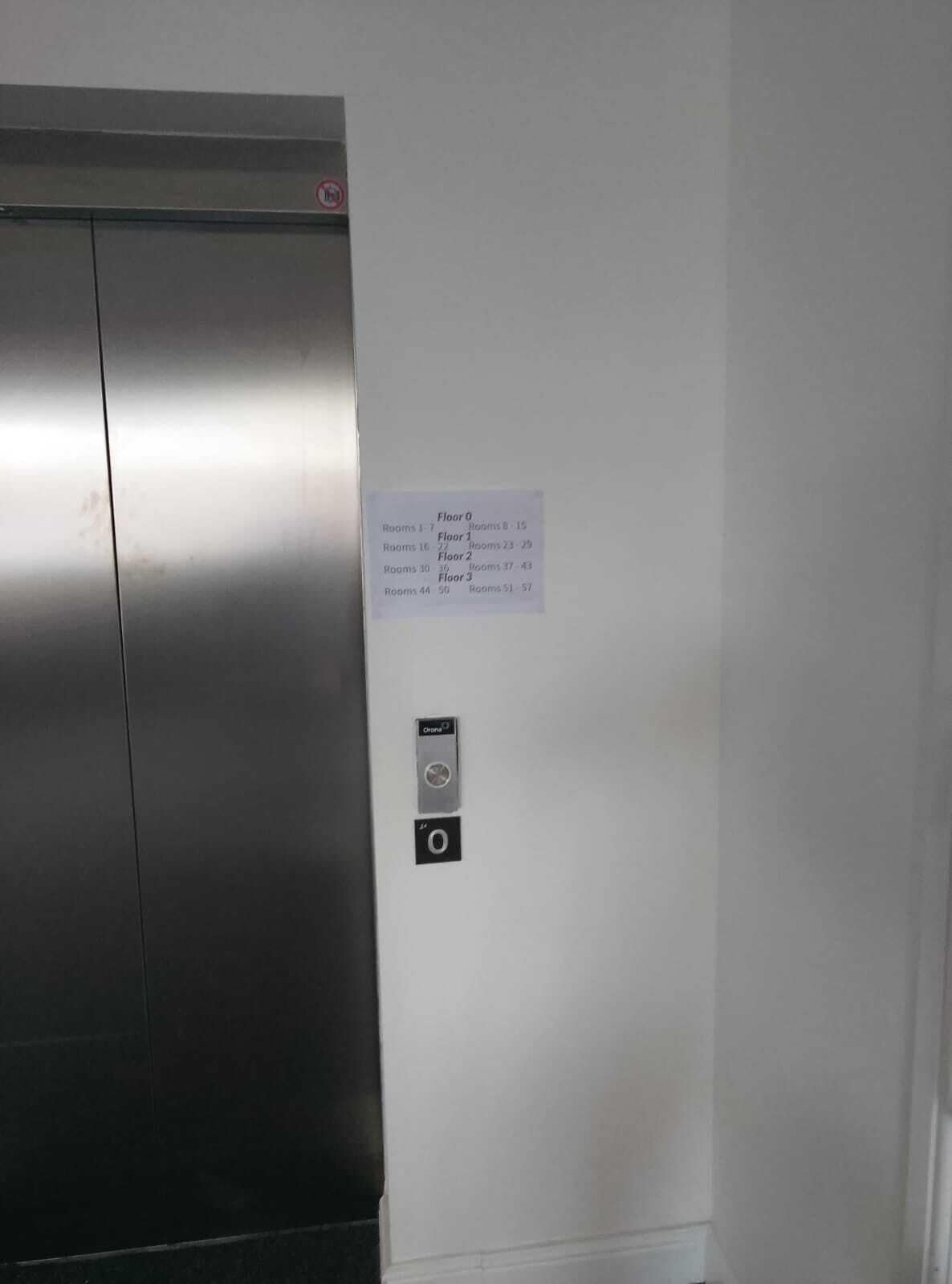 An elevator with a sign listing room numbers and their corresponding floor numbers.