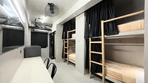 A modern room with bunk beds, a dining table, and a fan.