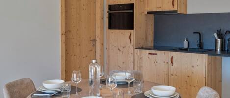 Un comedor con una mesa redonda dispuesta para cuatro, armarios de madera y una lámpara colgante moderna.