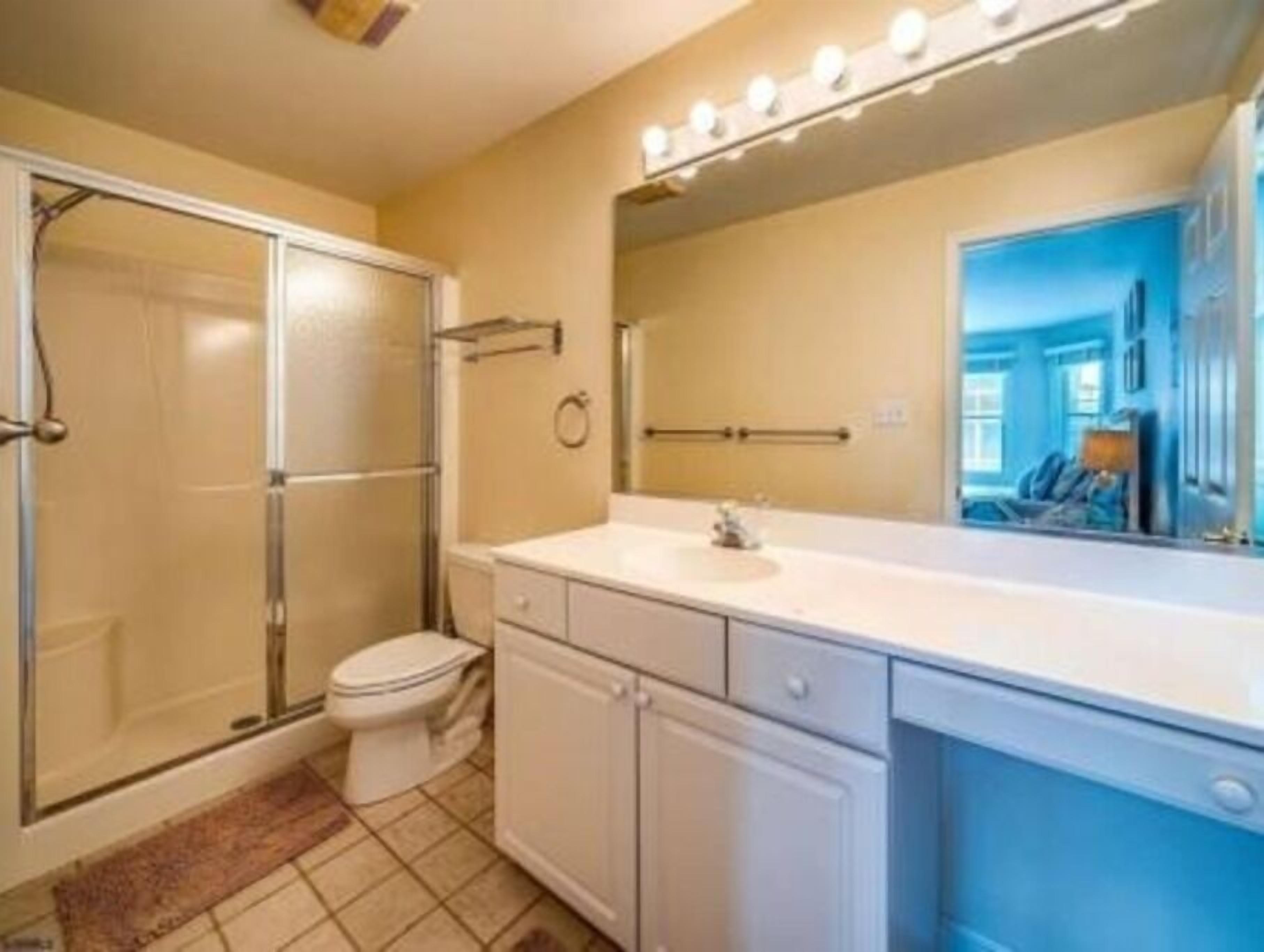 A bathroom with a shower, toilet, and vanity with a mirror.