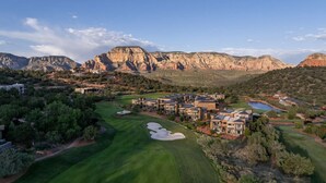 Un parcours de golf doté d’un club-house et de bâtiments résidentiels, le tout entouré de montagnes et de verdure.