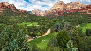 Un parcours de golf entouré de formations rocheuses rouges et d’une forêt verdoyante et dense.