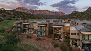 Un complexe résidentiel moderne composé de plusieurs maisons à deux étages, dotées de grandes fenêtres et de balcons, le tout situé dans un cadre montagneux.