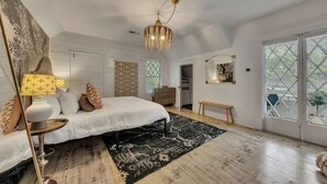 Un dormitorio con cama, mesita de noche, lámpara y un ventanal con vistas.