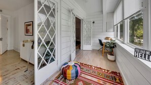 Una habitación espaciosa con suelo de madera, un sillón informal de tela, un tapete estampado y una ventana con el letrero 'You had me hello'.