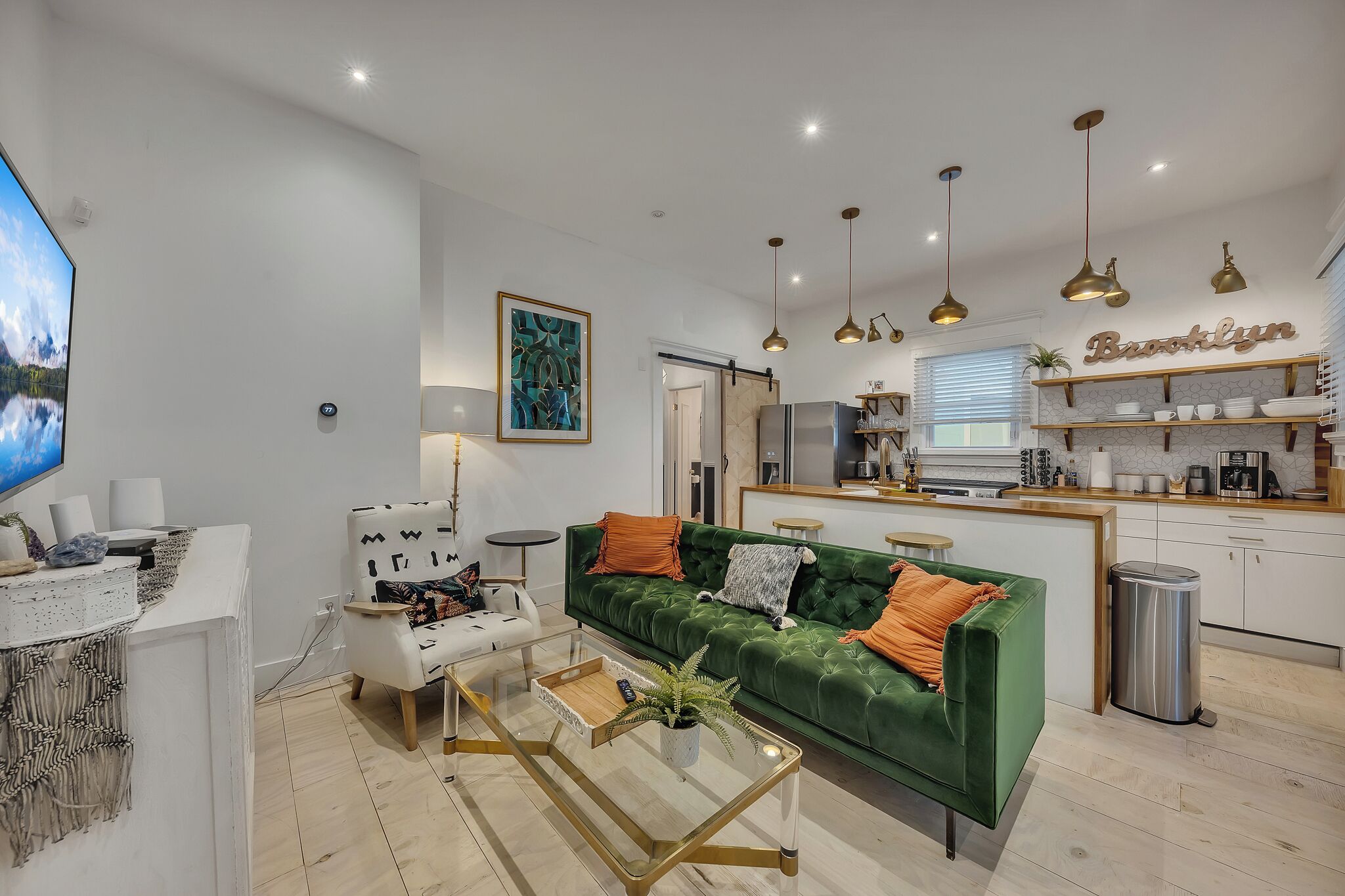 Un salon moderne avec un canapé vert, un fauteuil blanc et une table basse en verre.