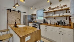 A modern kitchen with a central island, wooden countertops, and pendant lighting. - Midtown 2BR | Walk to Piedmont Park + Beltline (Atlanta)