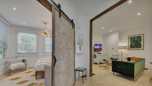 A modern bedroom with a bed, a green sofa, and a small table. - Midtown 2BR | Walk to Piedmont Park + Beltline (Atlanta)