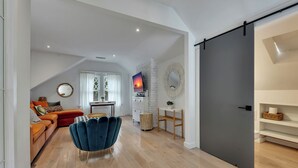 Un salon moderne avec un fauteuil bleu, un canapé et un téléviseur.