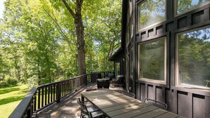 Une terrasse extérieure avec une table et des chaises, entourée d’arbres.