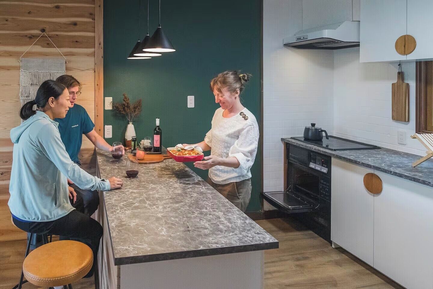 Uma cozinha moderna com bancada de mármore, forno embutido e luminária pendente.