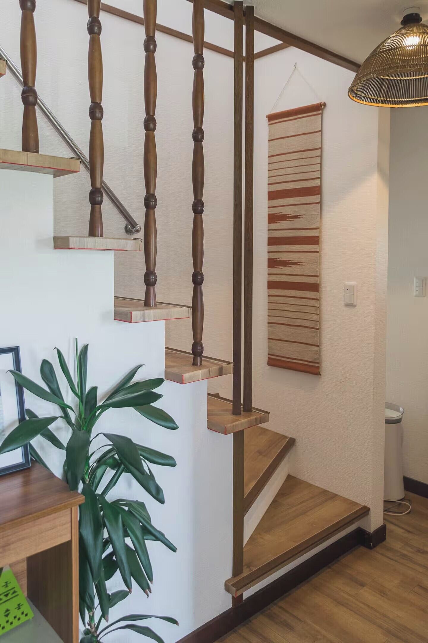 A staircase with wooden balusters and a woven wall hanging.
