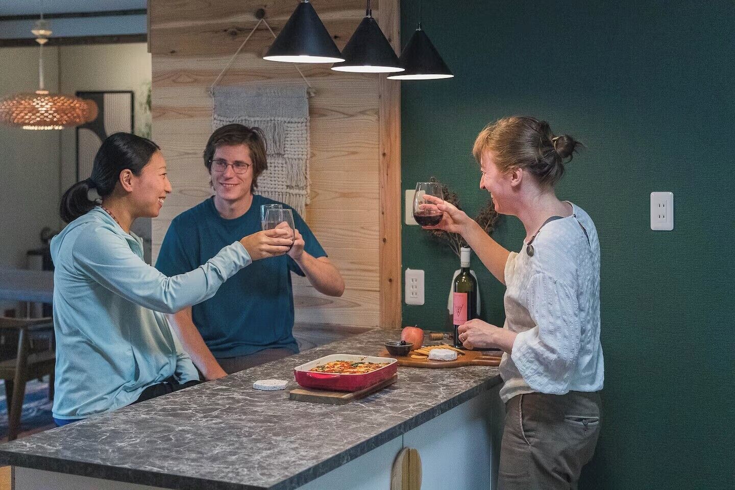 Une cuisine moderne dotée d’un plan de travail en marbre, de meubles en bois et de luminaires suspendus.