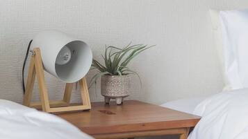 A wooden bedside table with a white lamp and a potted plant.
