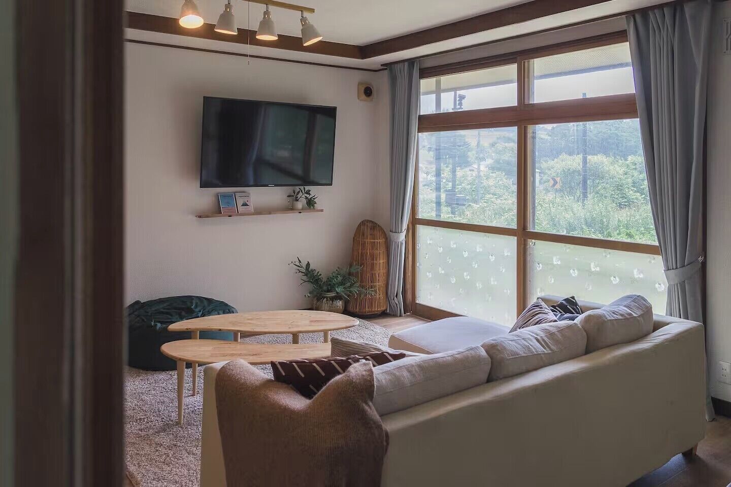 A living room with a large window, a flat-screen TV, a sofa, a coffee table, and a chair.