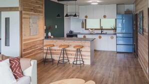 A modern kitchen with wooden accents, a central island with stools, and a blue refrigerator.
