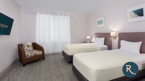 Une chambre d’hôtel avec deux lits, un canapé, une télévision et une fenêtre avec des rideaux.
