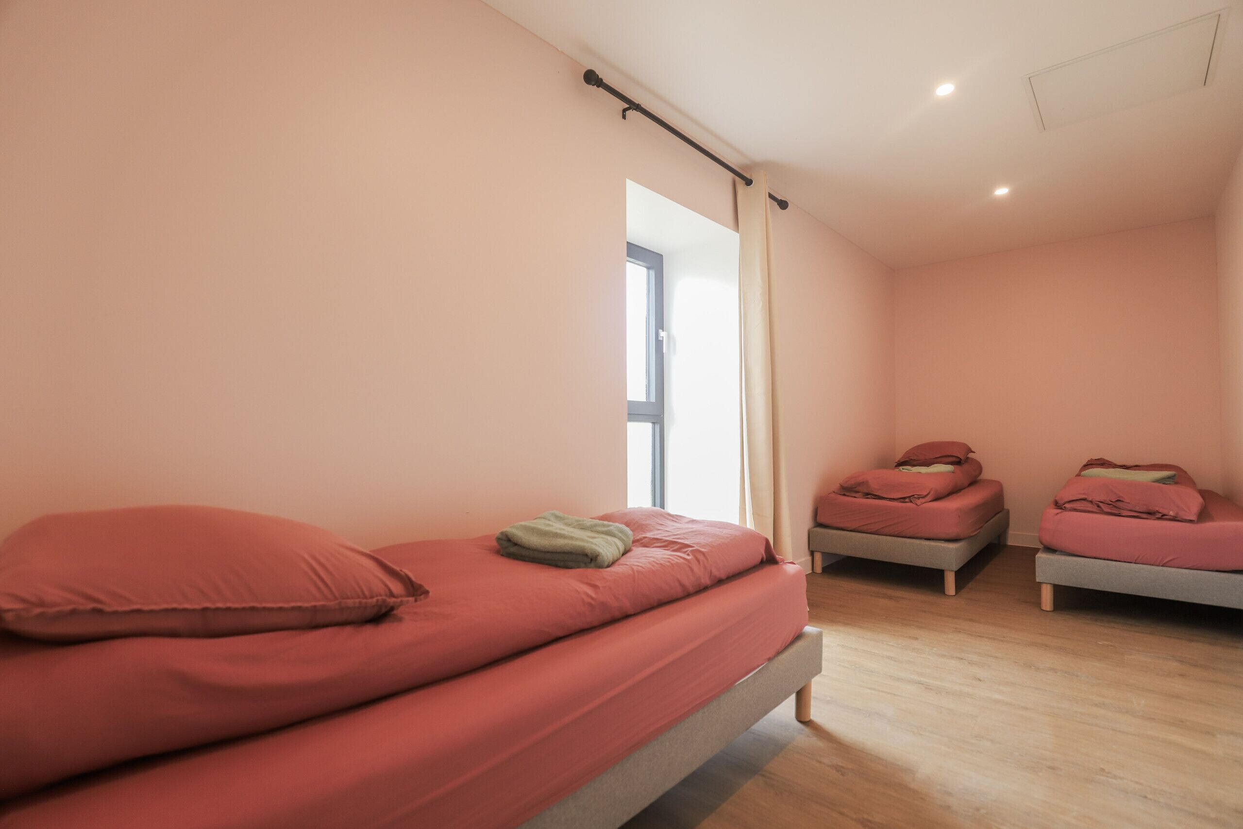 A room with two beds, a window, and a ceiling light.