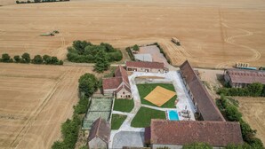 Vista aérea de una granja con establos, piscina y un extenso campo abierto.