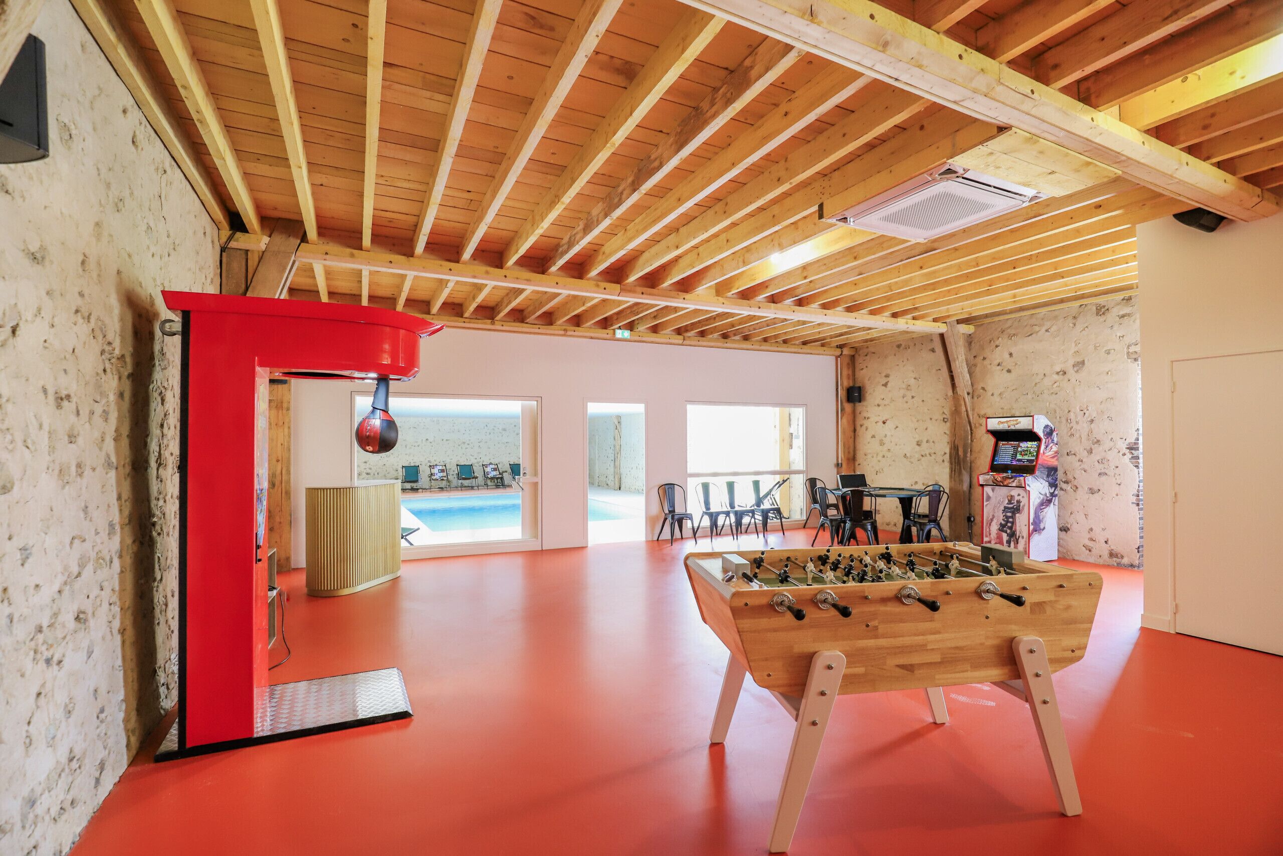 A room with a wooden ceiling, a foosball table, and a red cabinet.