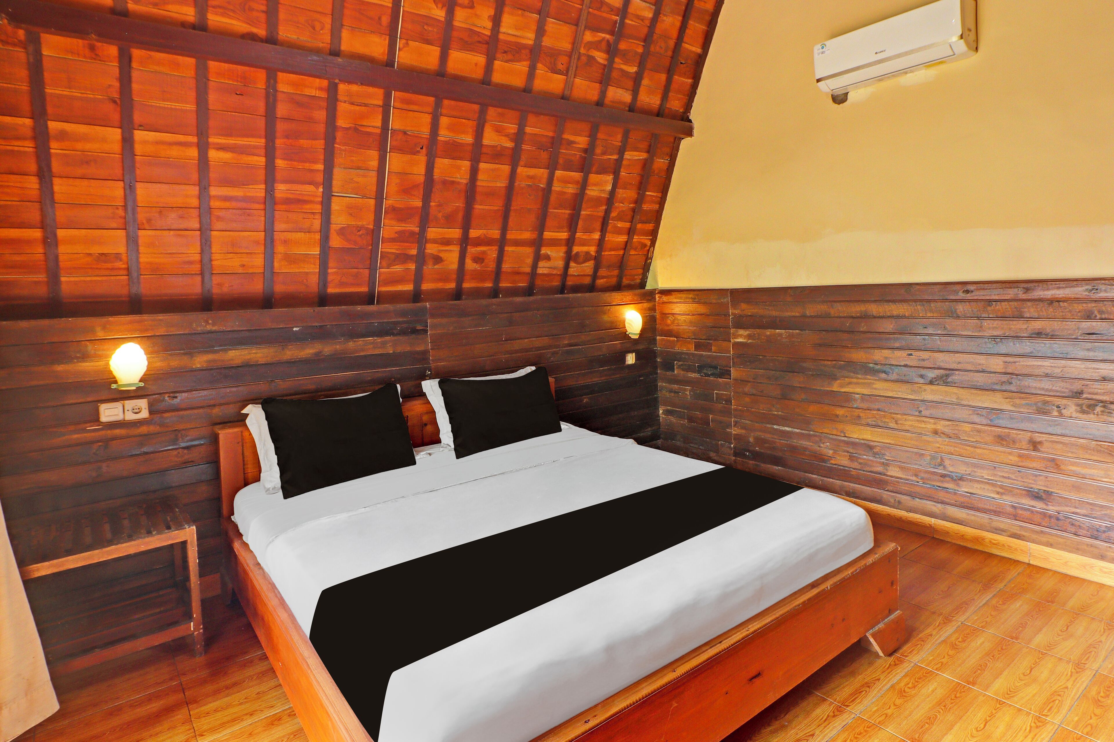 A wooden-framed room with a bed, nightstands, and a wall-mounted air conditioner.